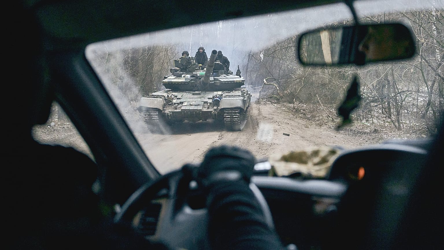 A Ukrainian tank with soldiers is seen through a car window close to the frontline near Kremenna in the Luhansk region, 15 January 2023