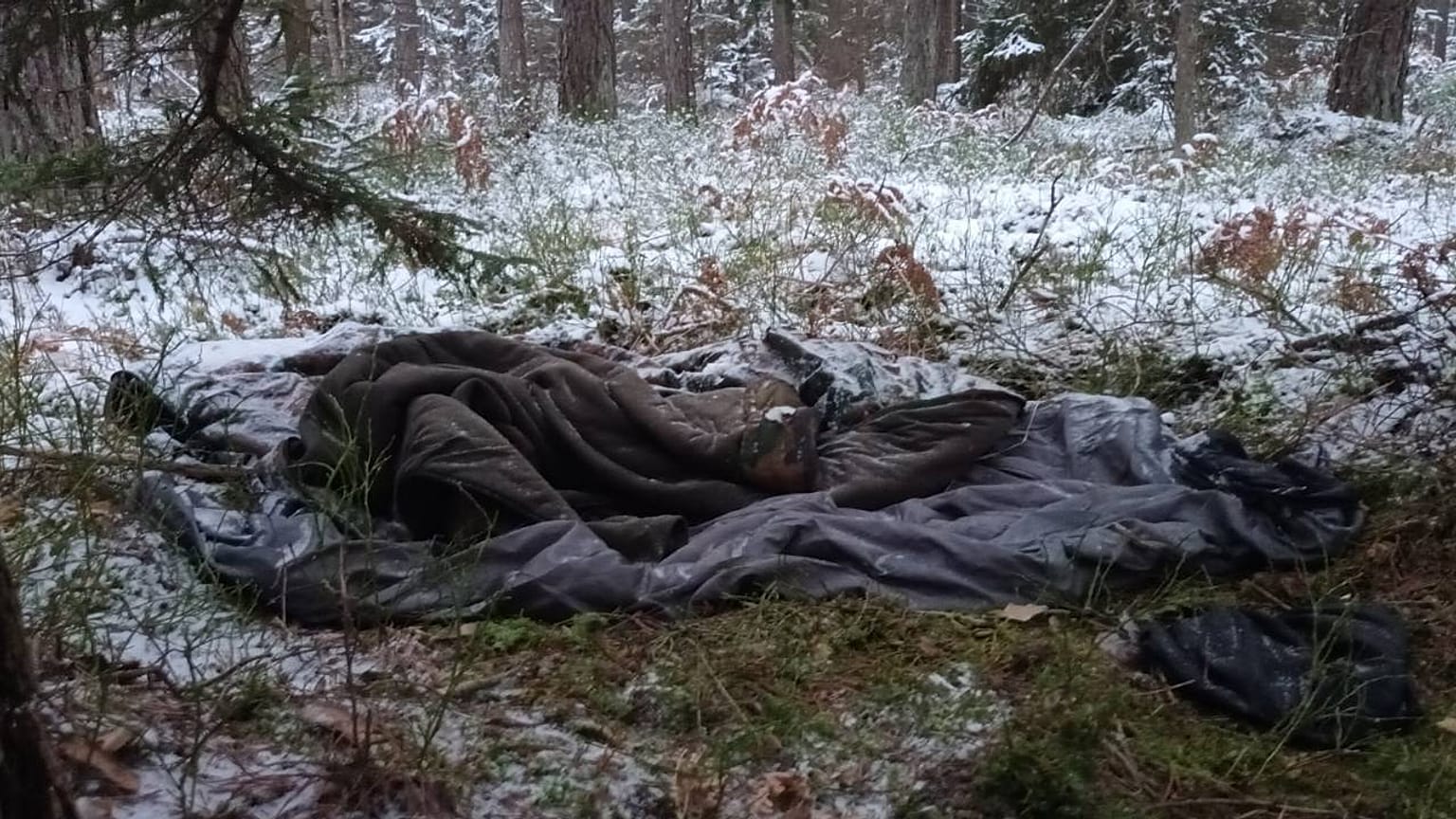 The border area is strewn with old sleeping bags and camping equipment. 