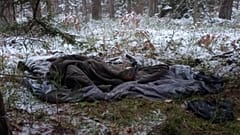 The border area is strewn with old sleeping bags and camping equipment. 