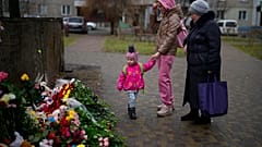 People pay their respects at the scene where a helicopter crashed into civil infrastructure on Wednesday, in Brovary, on the outskirts of Kyiv, Ukraine, Friday, Jan. 20, 2023.