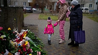 People pay their respects at the scene where a helicopter crashed into civil infrastructure on Wednesday, in Brovary, on the outskirts of Kyiv, Ukraine, Friday, Jan. 20, 2023.