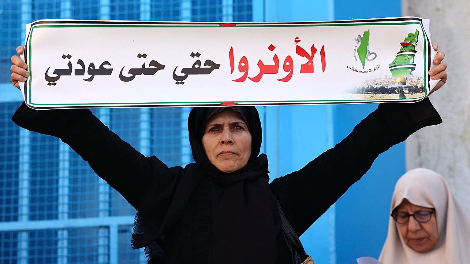 سيدة فلسطينية تحمل لافتة خلال مظاهرة خارج مقر وكالة الأمم المتحدة لإغاثة وتشغيل اللاجئين (الأونروا) في مدينة غزة ديسمبر 2022.