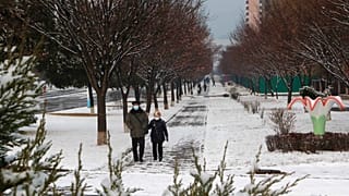 Kuzey Kore'nin başkenti Pyongyang'ın Pothonggang bölgesinde karlı bir caddede yürüyen vatandaşlar 