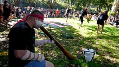 Egy ausztrál őslakos fújja ősi hangszerét, a didzseridut