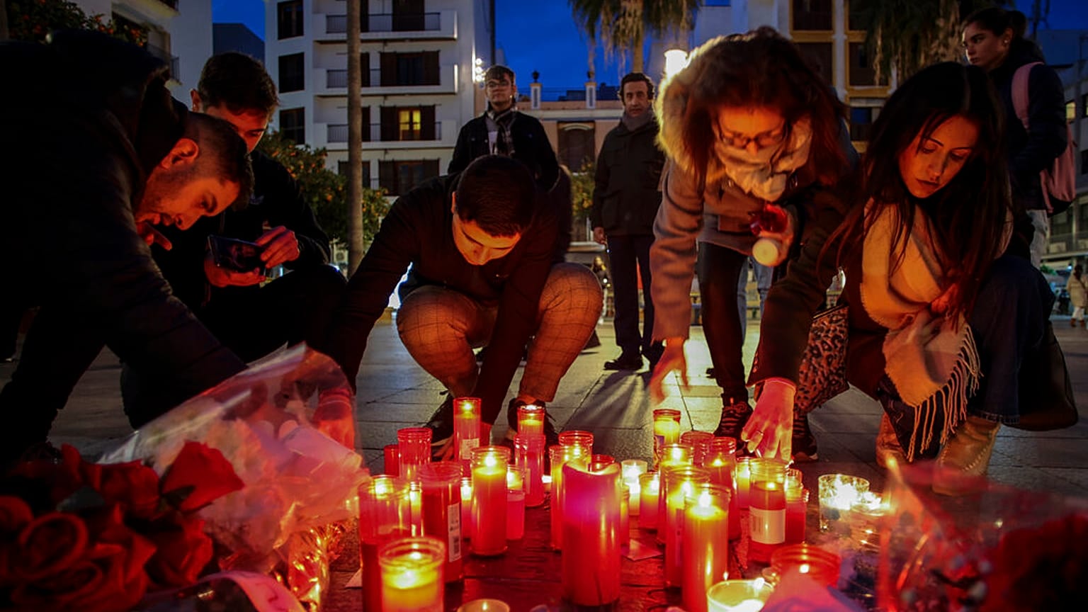 Una mujer se arrodilla junto al monumento en memoria del sacristán de una iglesia asesinado el miércoles en Algeciras, sur de España, jueves 26 de enero de 2023.