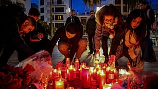 Una mujer se arrodilla junto al monumento en memoria del sacristán de una iglesia asesinado el miércoles en Algeciras, sur de España, jueves 26 de enero de 2023.