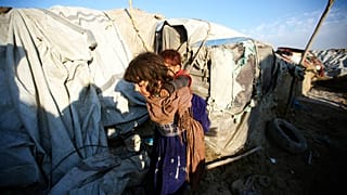 Afganistan'ın başkenti Kabil'e yakın mesafedeki Teymeni mülteci kampında, kardeşini sırtına alan bir kız çocuğu