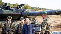 Deutschlands Kanzler Olaf Scholz mit Bundeswehrsoldaten vor einem Leopard-Panzer.