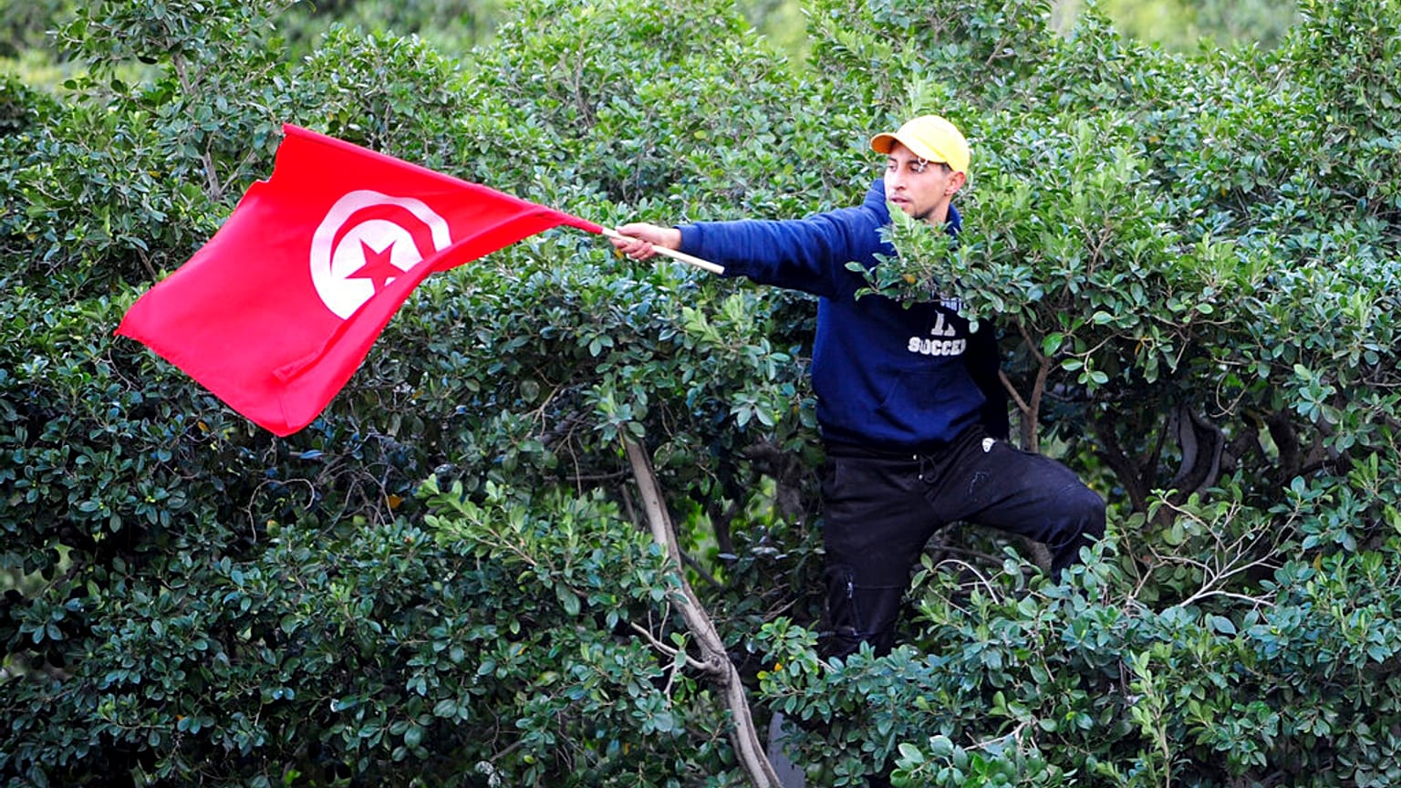 Un homme brandit un drapeau tunisien lors d'une manifestation contre le président tunisien Kaïs Saïed dans le centre-ville de Tunis, en Tunisie, samedi 14 janvier 2023.