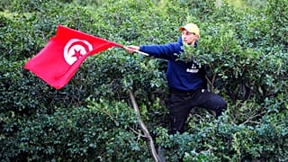 Un homme brandit un drapeau tunisien lors d'une manifestation contre le président tunisien Kaïs Saïed dans le centre-ville de Tunis, en Tunisie, samedi 14 janvier 2023.