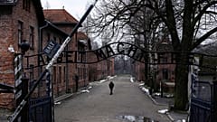 مردی در کنار دروازه "Arbeit Macht Frei" (کار شما را آزاد می کند) در اردوگاه کار اجباری و کشتار آلمان نازی سابق آشویتس-بیرکناو در لهستان، پنجشنبه، ۲۶ ژانویه ۲۰۲۳ 