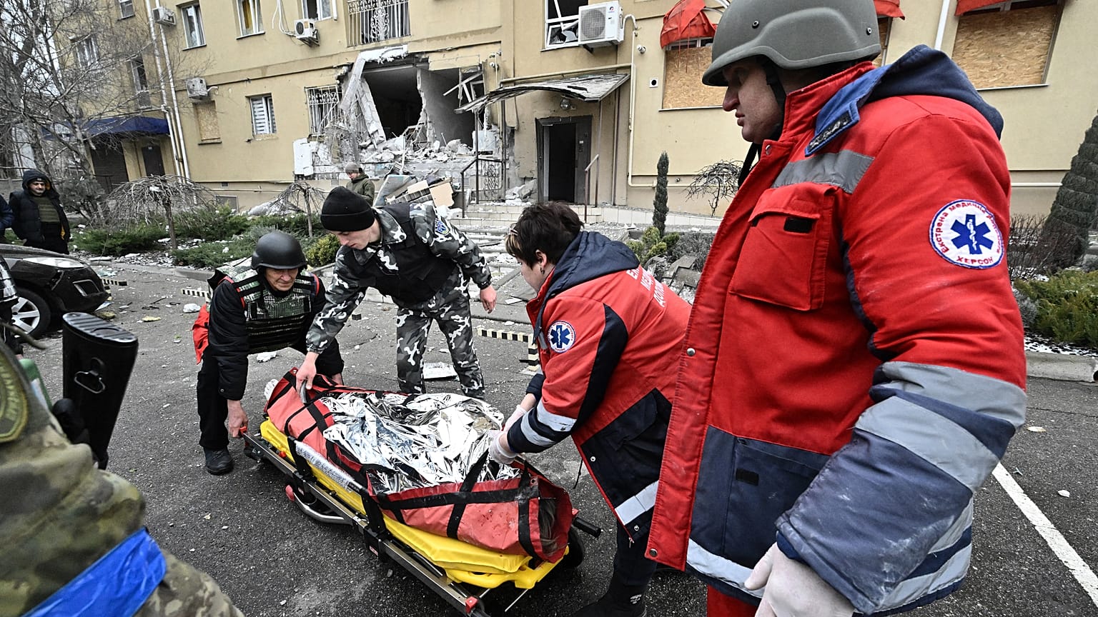 Ukrainian medics carry the body of a local resident killed in a residential building after a Russian shelling in Kherson, southern Ukraine, on January 29, 2023.