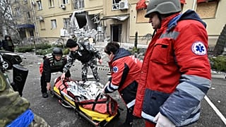 Ukrainian medics carry the body of a local resident killed in a residential building after a Russian shelling in Kherson, southern Ukraine, on January 29, 2023.