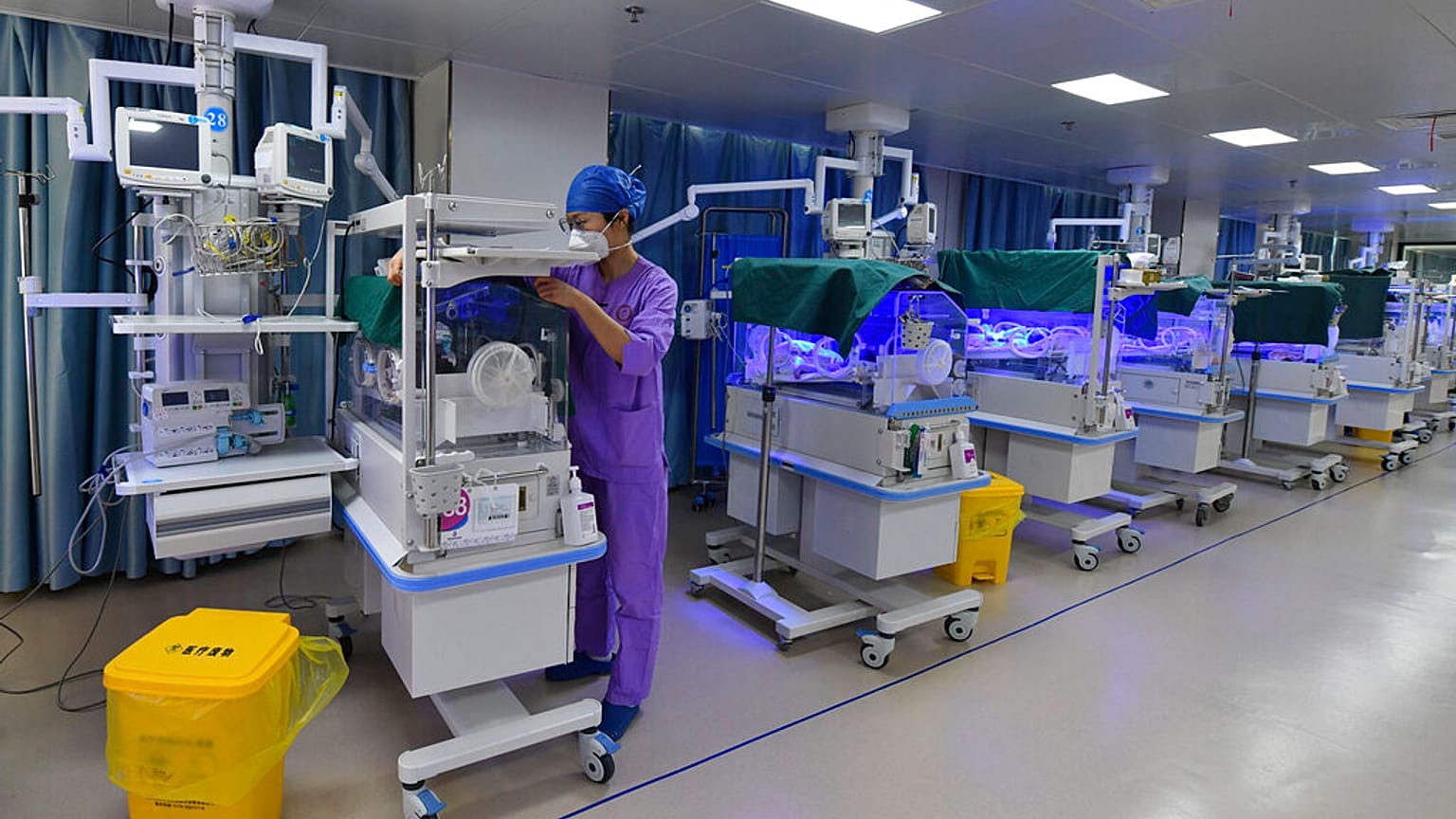 Çin'de bir doğumevinde, yeni doğmuş bir bebeği kontrol eden bir hemşire 