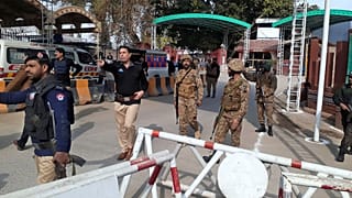 Army soldiers and police officers clear the way for ambulances rushing toward a bomb explosion site, at the main entry gate of police offices, in Peshawar, Pakistan, Monday, J