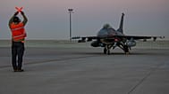FILE: In this handout photo from the US Air Force, an airman guides an F-16 Fighting Falcon during training at Al-Udeid Air Base, 24 January 2022