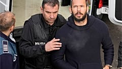 Police officers escort Andrew Tate, right, handcuffed to his brother Tristan Tate, to the Court of Appeal in Bucharest, Romania