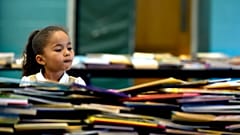 Mädchen vor einem Bücherstapel