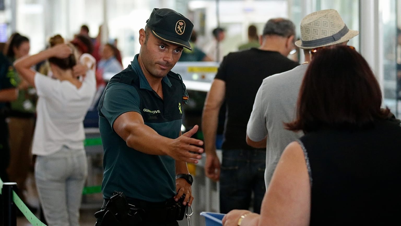 A civil guard officer gestures as passengers pass the security control at the Barcelona airport in Prat Llobregat, Spain, Aug. 14, 2017. 