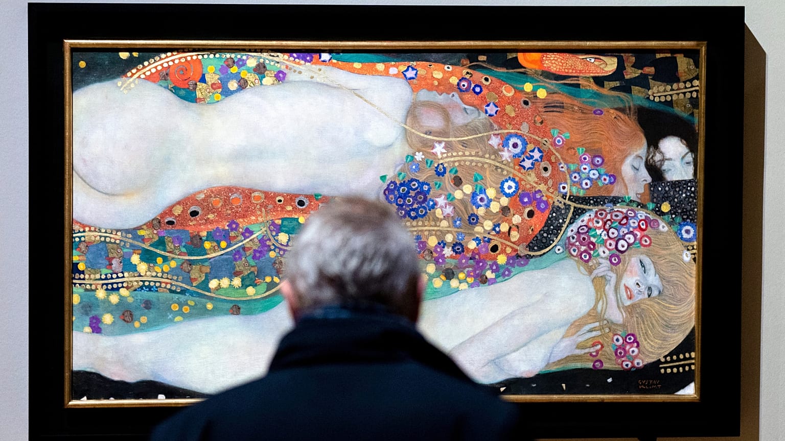 A visitor looks at the painting 'Water Serpents II'