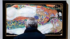 A visitor looks at the painting 'Water Serpents II'