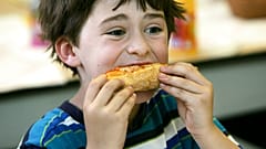 ABD'de bir okulda yıl sonu partisinde pizza yiyen 7 yaşındaki Henry Wineman isimli öğrenci (arşiv)