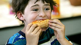 ABD'de bir okulda yıl sonu partisinde pizza yiyen 7 yaşındaki Henry Wineman isimli öğrenci (arşiv)