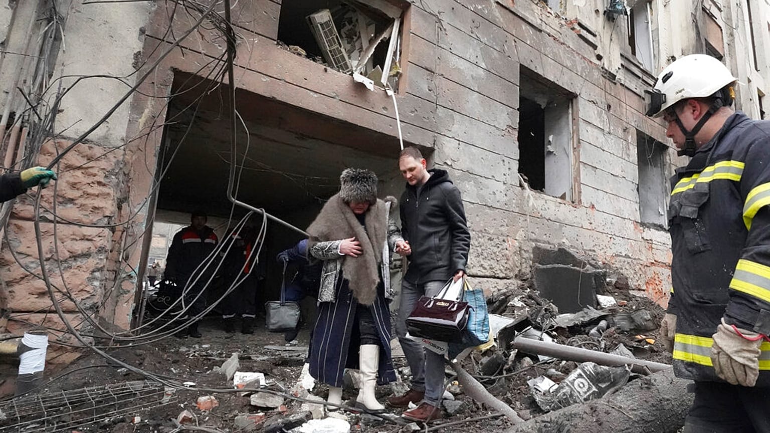Un homme aide une habitante de Kharkik à sortir de son immeuble touché par une frappe russe, 5 février 2023