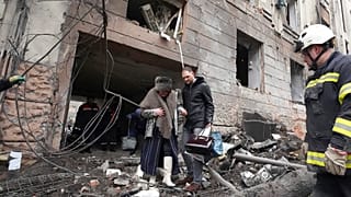 Un homme aide une habitante de Kharkik à sortir de son immeuble touché par une frappe russe, 5 février 2023