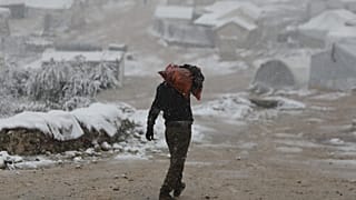 نازح سوري يحمل الحطب كمصدر للتدفئة في مخيم بشمال غرب سوريا