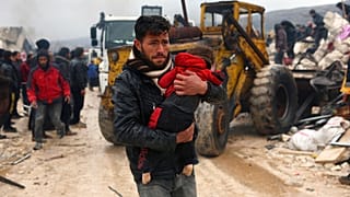 Un homme porte le corps d'une victime du tremblement de terre dans le village de Besnia, près de la frontière turque, dans la province d'Idlib, en Syrie, lundi 6 février 2023.