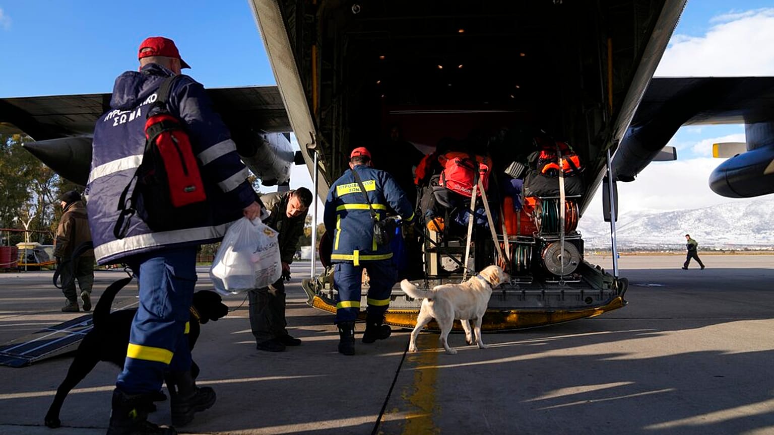 Des pompiers grecs accompagnés de chiens montent à bord d'un avion militaire à la base aérienne d'Elefsina, dans l'ouest d'Athènes, en Grèce, lundi 6 février 2023.