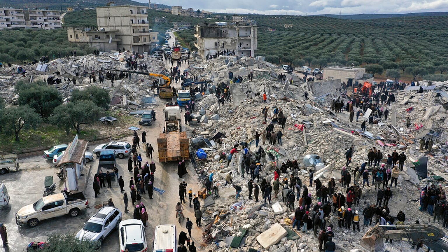 عمال دفاع مدني وسكان يفتشون بين أنقاض المباني المنهارة في بلدة حارم قرب الحدود التركية بمحافظة إدلب السورية، 6 شباط 2023