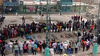 Residents stand around the bodies of persons who perished in recent landslides in Camana, Peru, Monday 6 February, 2023
