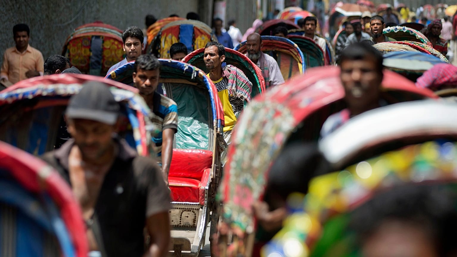 Rickshaw pullers wait in a line, awaiting passengers in Dhaka, Bangladesh