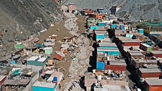 Residents walk on a street covered with debris caused by a landslide, in Camana, Peru, Tuesday.