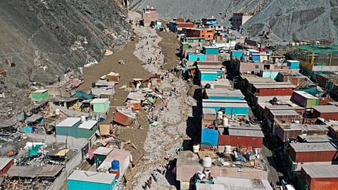Residents walk on a street covered with debris caused by a landslide, in Camana, Peru, Tuesday.