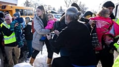 Parents and their children are loaded onto a warming bus after a bus crashed into a daycare in Quebec