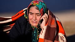 A woman speaks on her cellphone as rescuers search a destroyed building in Gaziantep, southeastern Turkey, Thursday, Feb. 9, 2023