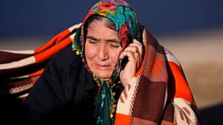 A woman speaks on her cellphone as rescuers search a destroyed building in Gaziantep, southeastern Turkey, Thursday, Feb. 9, 2023