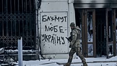 Ukrainischer Soldat vor einem Plakat in Bachmut mit derAufschrift "Bachmut liebt die Ukraine"