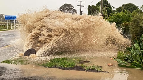 Water gushes from a storm drain access port on a street in Te Awanga, southeast of Auckland, New Zealand.