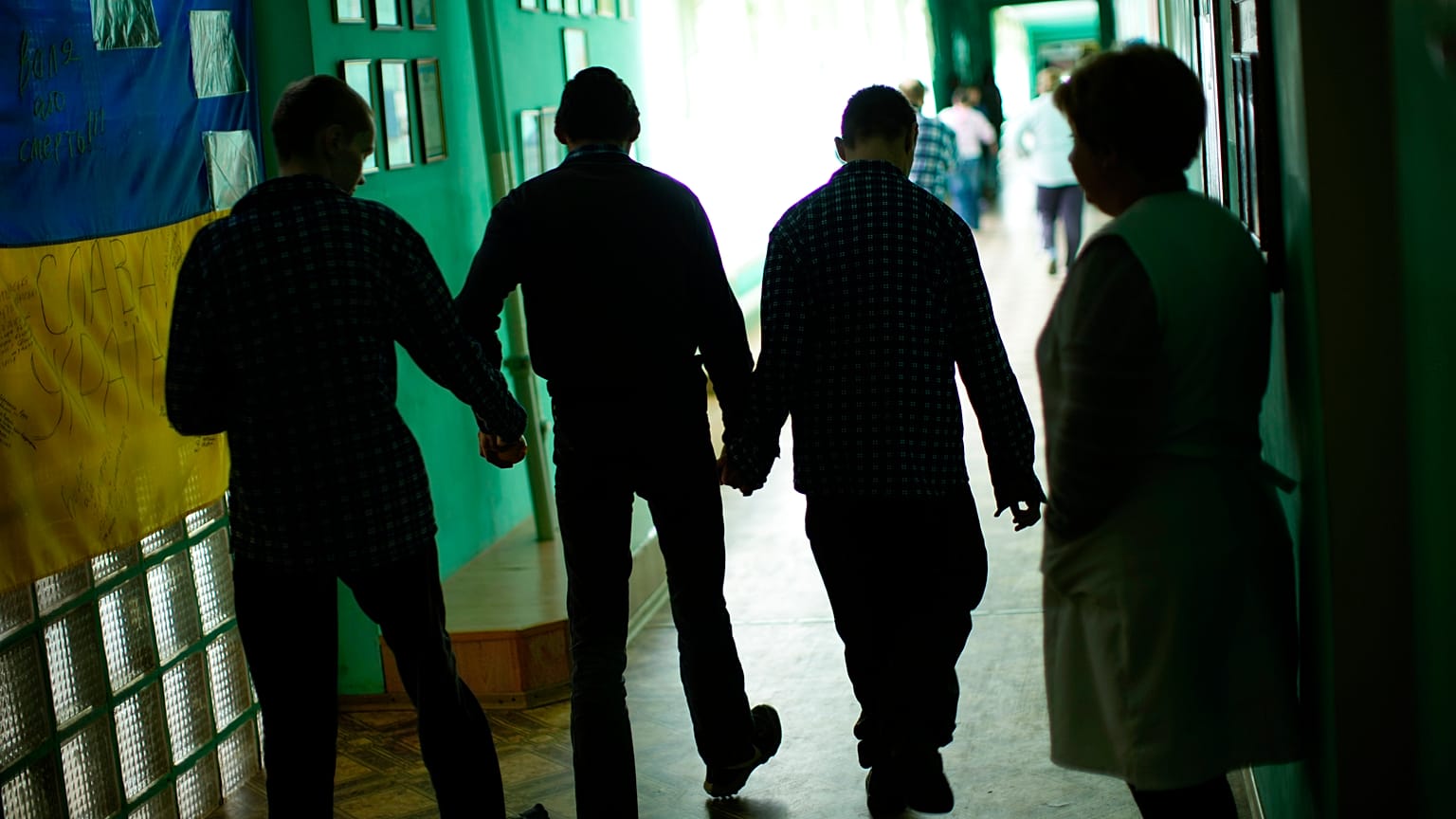 Residents walk along a corridor after lunch time in a facility for people with mental and physical disabilities in the village of Tavriiske, Ukraine, Tuesday, May 10, 2022.