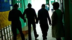 Residents walk along a corridor after lunch time in a facility for people with mental and physical disabilities in the village of Tavriiske, Ukraine, Tuesday, May 10, 2022.