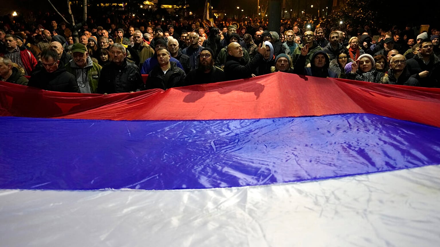 A tüntetők egy óriási szerb zászlóval a kezükben Belgrádban, 2023. február 15-én