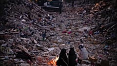 Membros de uma família desalojada pelo sismo, tentam aquecer-se numa fogueira, em Antáquia, Turquia