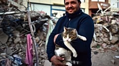 Férfi a macskájával, akit egy összedőlt épületből mentettek ki a dél-törökországi Kahramanmarasban