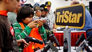 Gyerekek próbálgatnak fegyvereket az NRA (Nemzeti Lőfegyverszövetség) éves összejövetelén 2013-ban Houstonban
