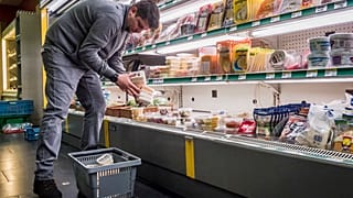 A worker removes expired food in a local supermarket in Brussels.