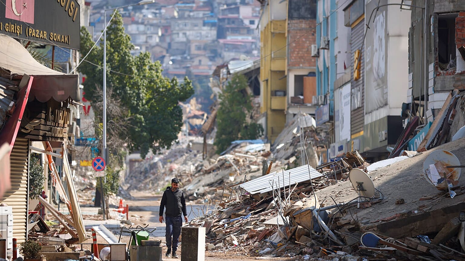 Homem passa por rua destruída pelos sismos em Antakya, Turquia
